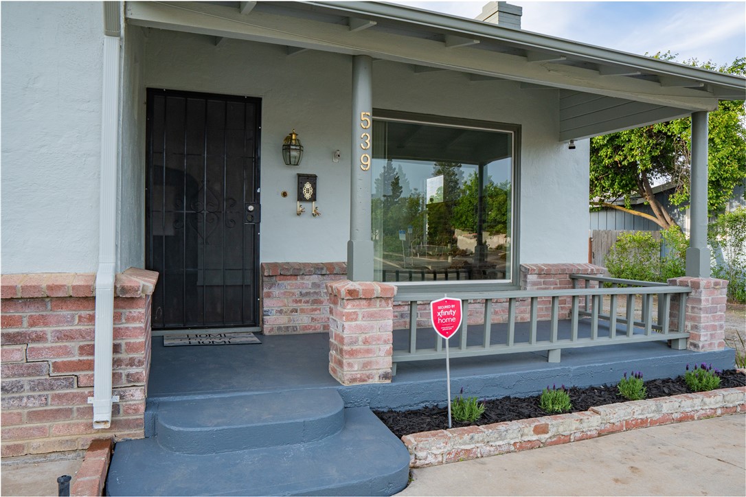 Home exterior with a covered porch, black security door, and brick accents.