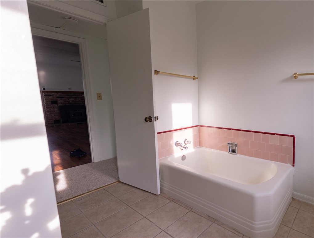 Bathroom with a white bathtub, pink tile surround, and red tile trim.
