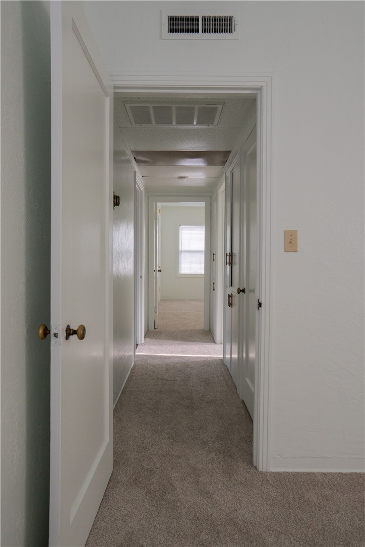 Carpeted hallway with multiple white doors and a window at the far end.