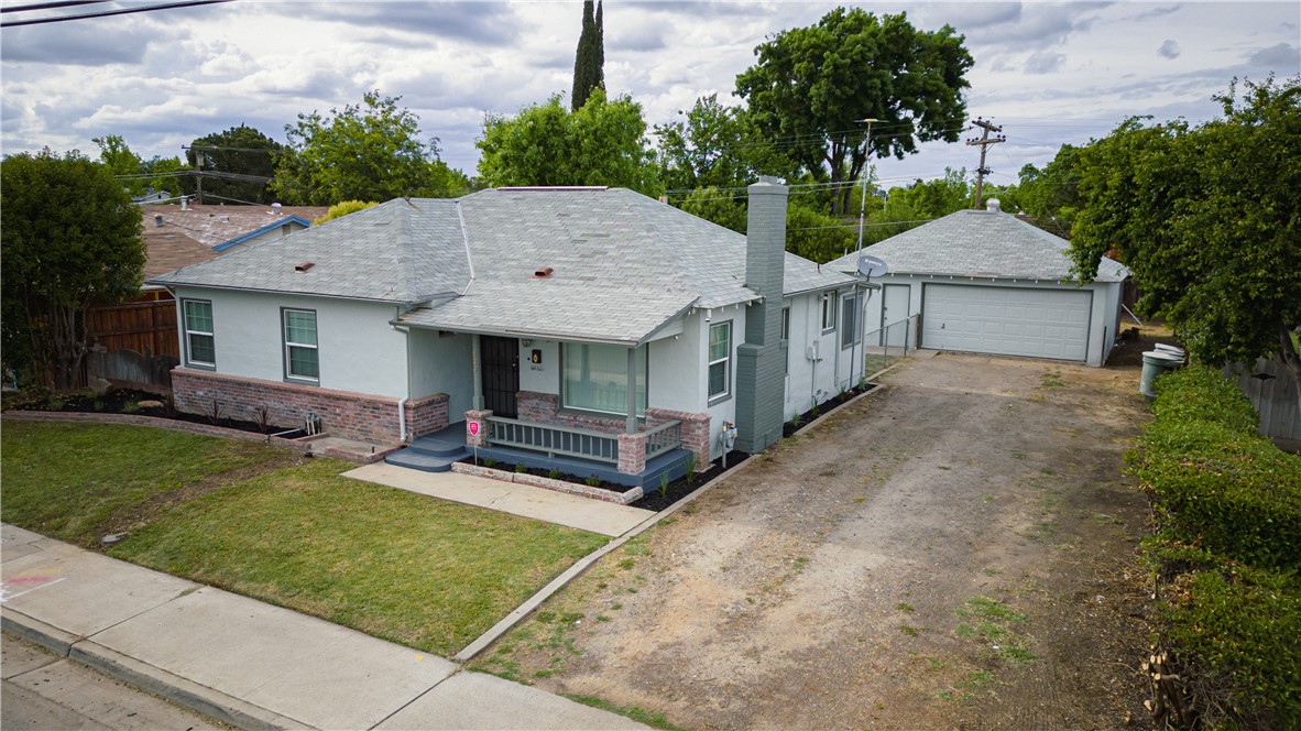 Single-story gray house with brick accents, a covered porch, front lawn, and long driveway to the garage.