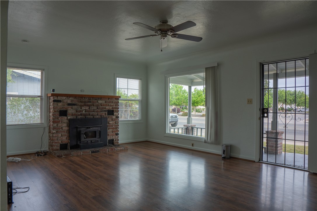 Unfurnished living room with a brick fireplace, wood stove, and dark wood-look floors.