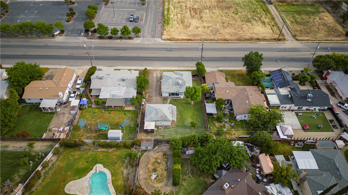 Aerial view of homes and backyards along a broad road, with a swimming pool in one yard.