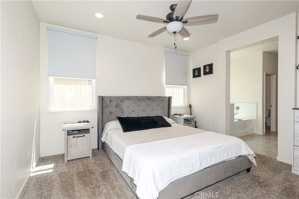 Bedroom with a gray upholstered bed, white bedding, and an open doorway to the bathroom.