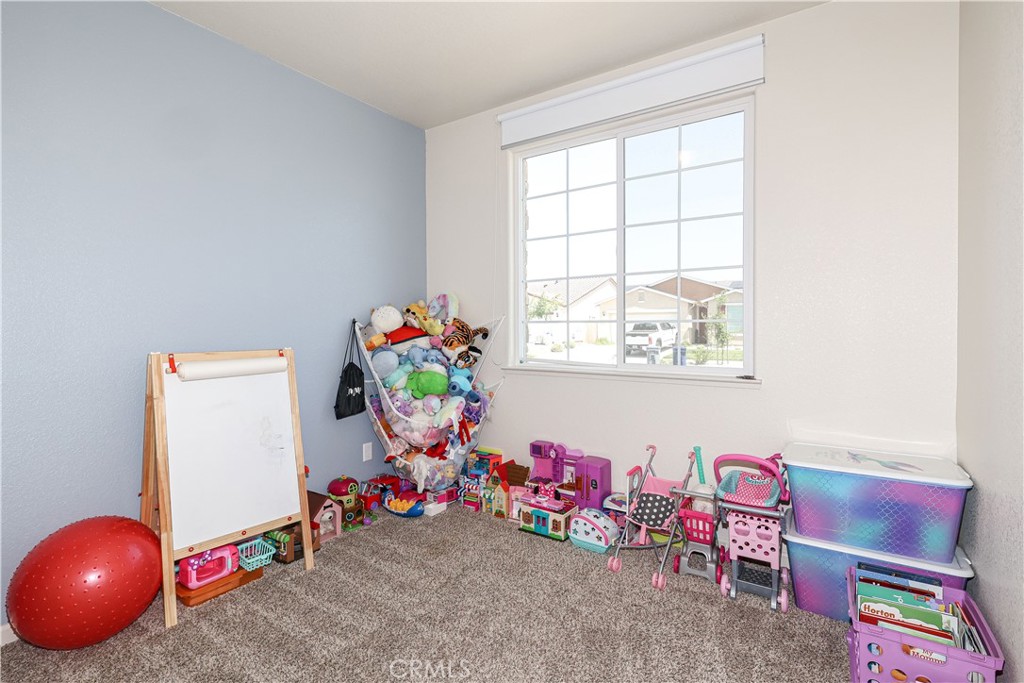Children’s playroom with a whiteboard easel, stuffed animals, toy houses, and pink strollers.