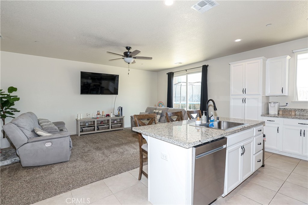 Open-plan kitchen with a granite island adjoining a carpeted living room and dining area.