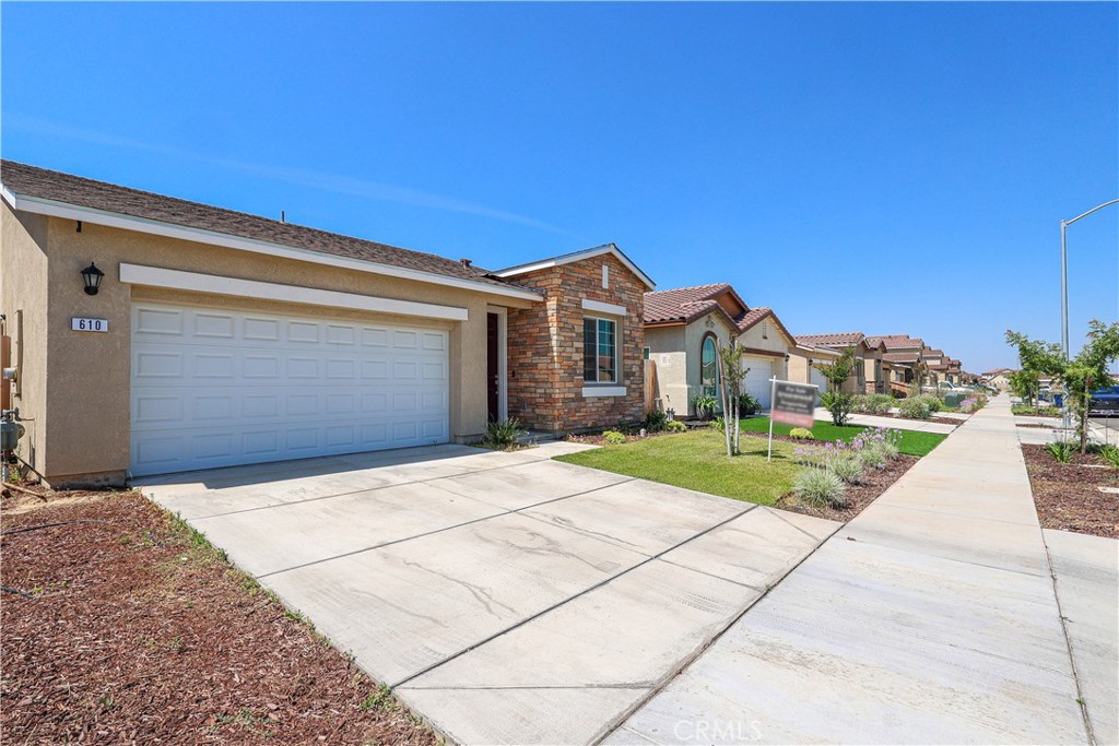 Front exterior of 610 Marybelle Drive, with a two-car garage, brick entry, driveway, and landscaped yard.