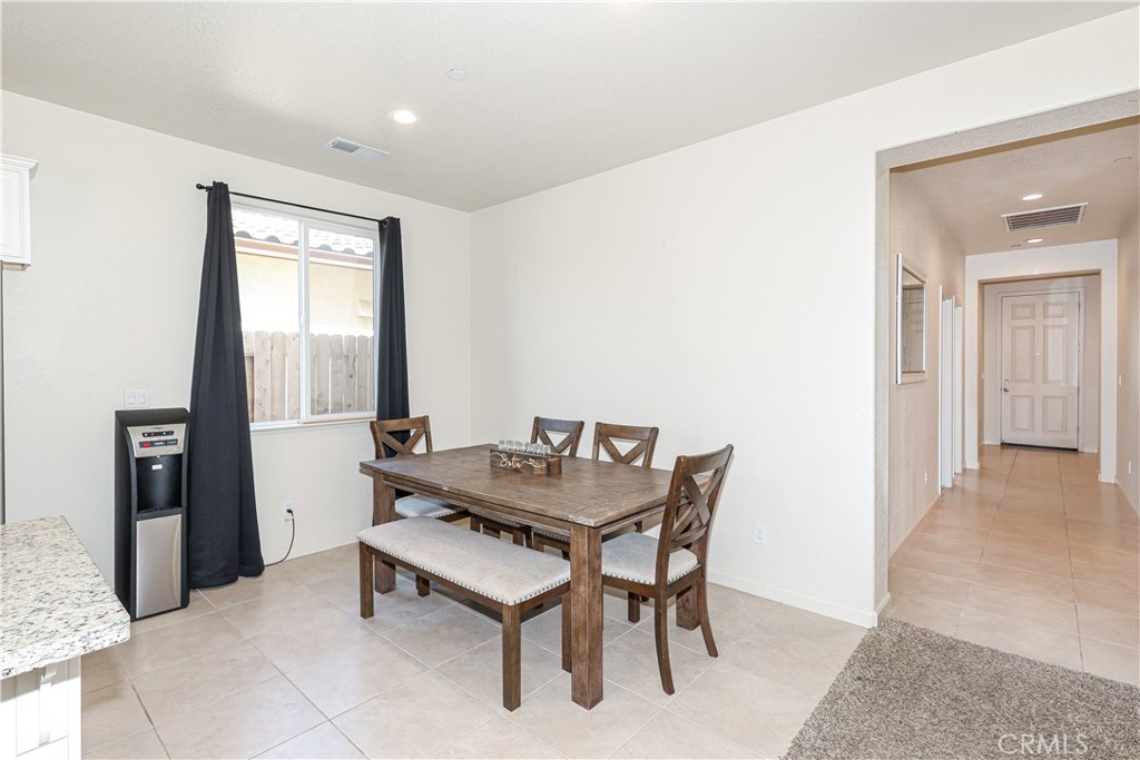 Dining room with a wooden table and chairs beside a window with dark curtains.