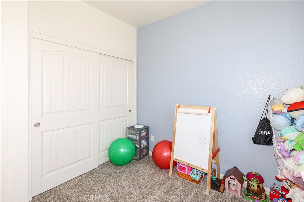 Children’s playroom with blue walls, white sliding closet doors, an easel, and colorful toys.