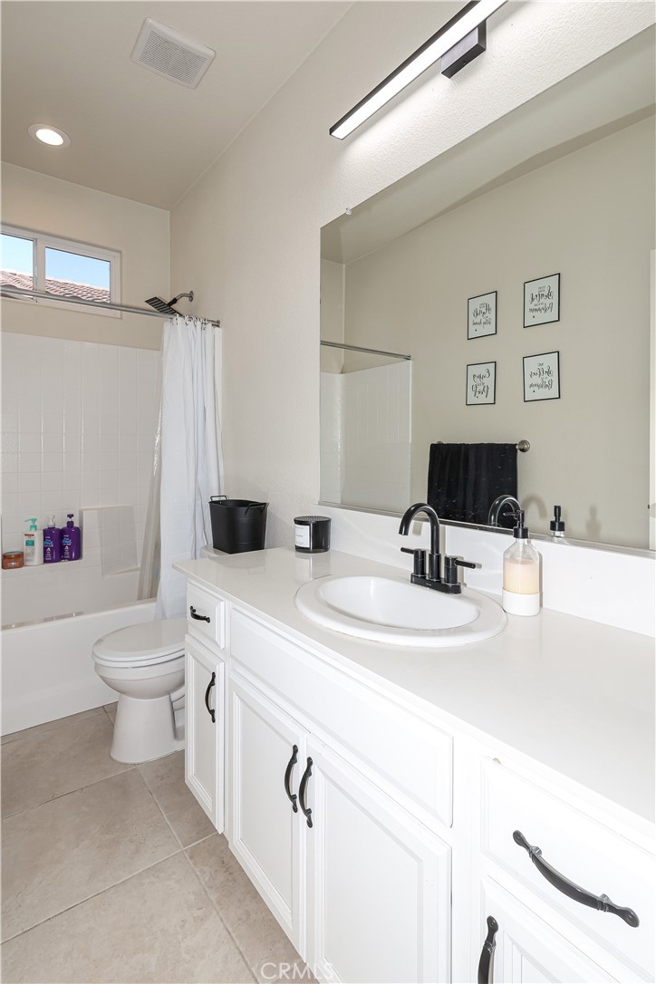 Bathroom with a long white vanity, oval sink, large mirror, and tub with a white shower curtain.