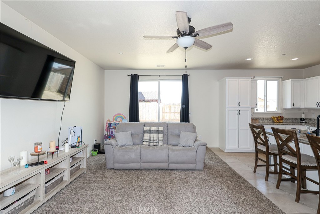 Living room with gray sofa, wall-mounted TV, and open dining area and kitchen.