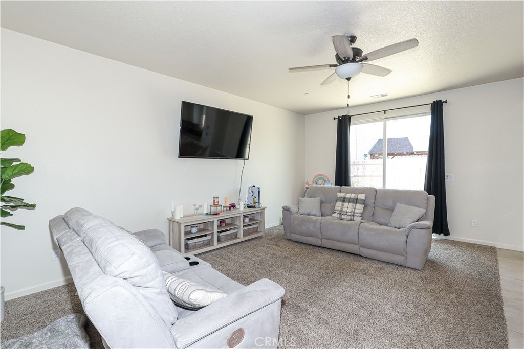 Living room with two gray sofas, a wall-mounted television, and a curtained window.