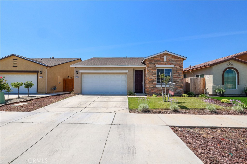 Single-story home with a stone facade, two-car garage, driveway, and front lawn.