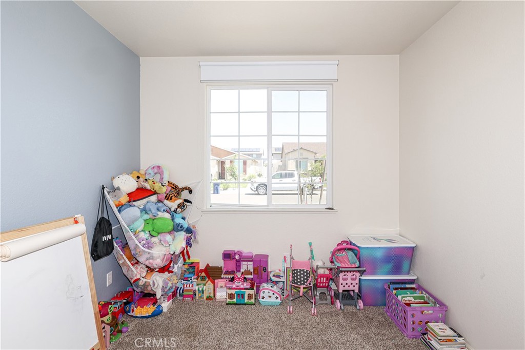 Children's playroom with toys and miniature furniture beneath a large window.