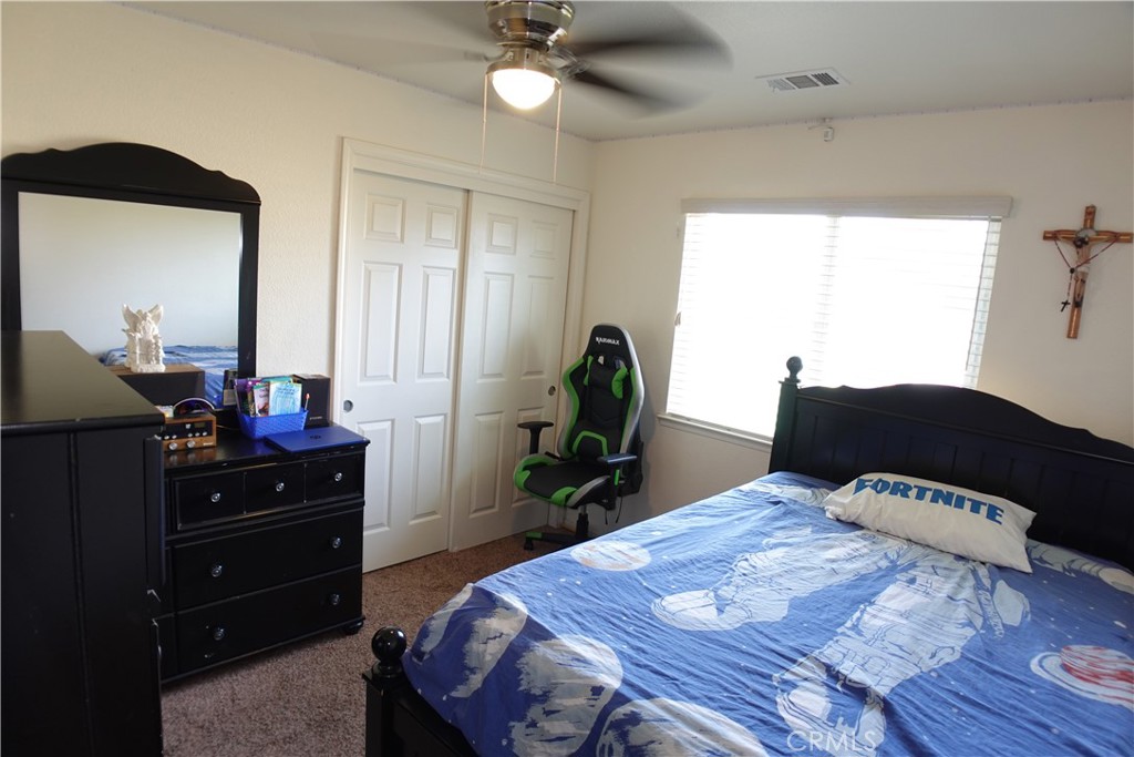 Bedroom with blue Fortnite bedding, black furniture, and a green-and-black gaming chair.