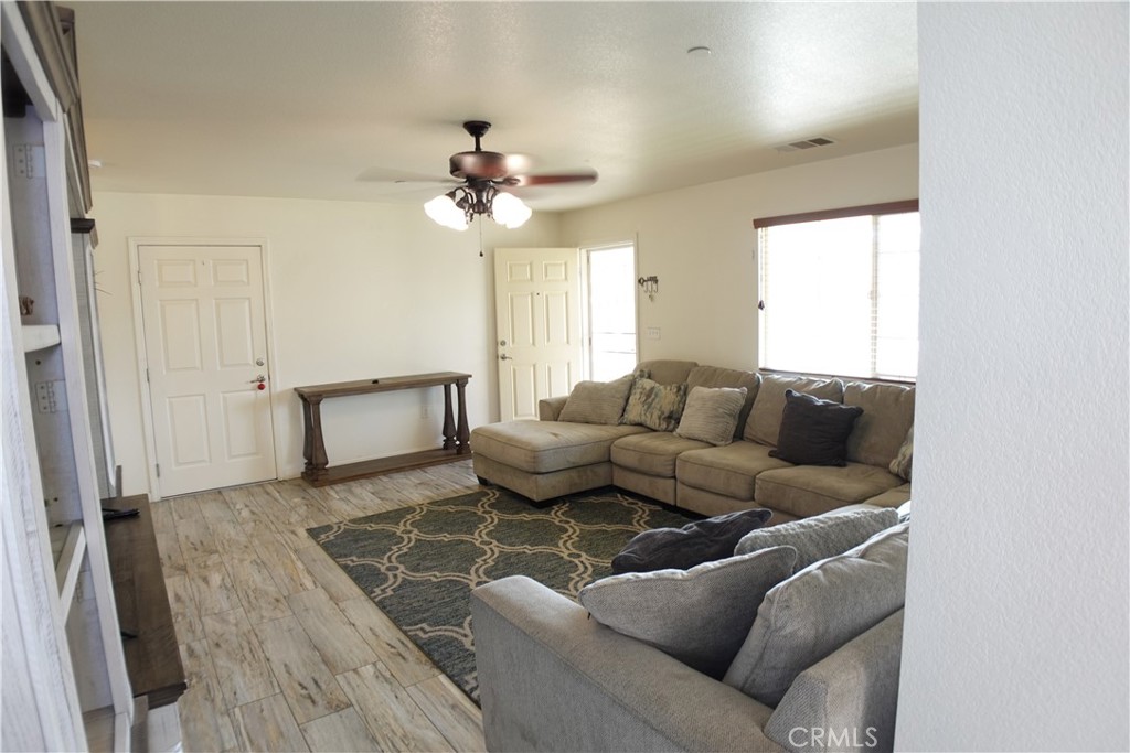 Furnished living room with beige sectional sofas, patterned rug, and wood-look tile flooring.