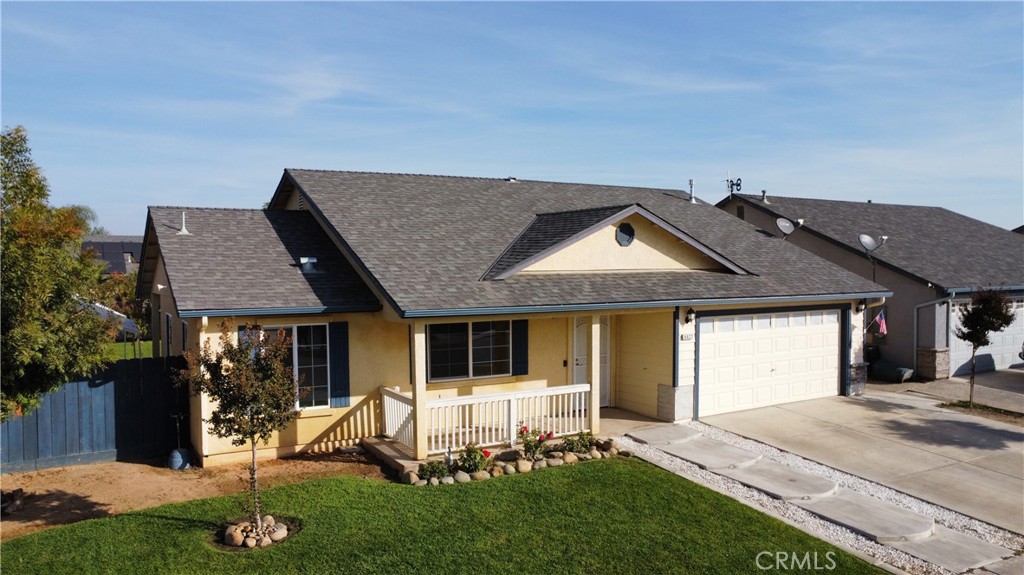 Yellow single-story house with a covered porch, white two-car garage, and front lawn.