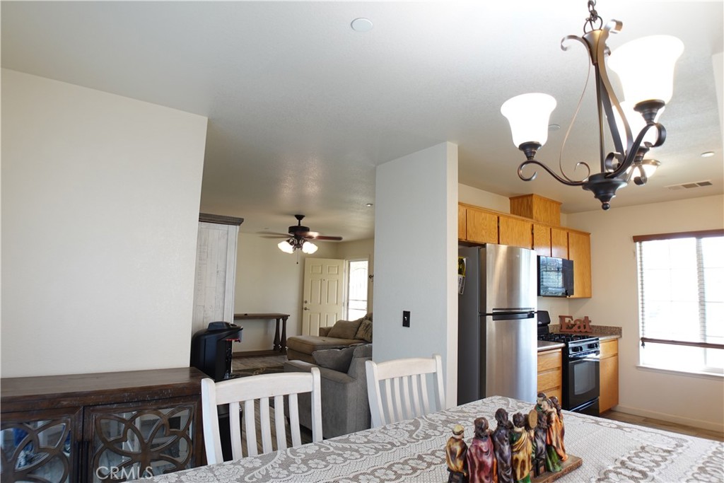 Open-plan kitchen and dining area with oak cabinets, stainless appliances, and a gray sectional sofa.