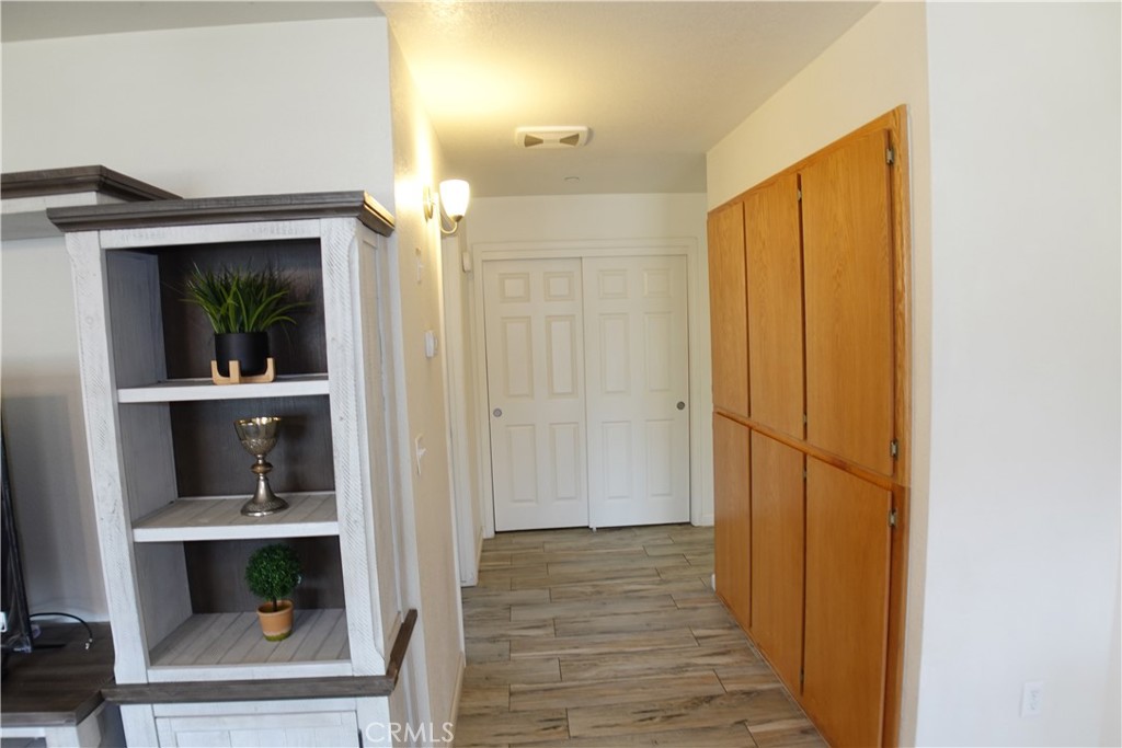 Hallway with wood-look tile flooring, tall honey-colored cabinets, and white double doors.