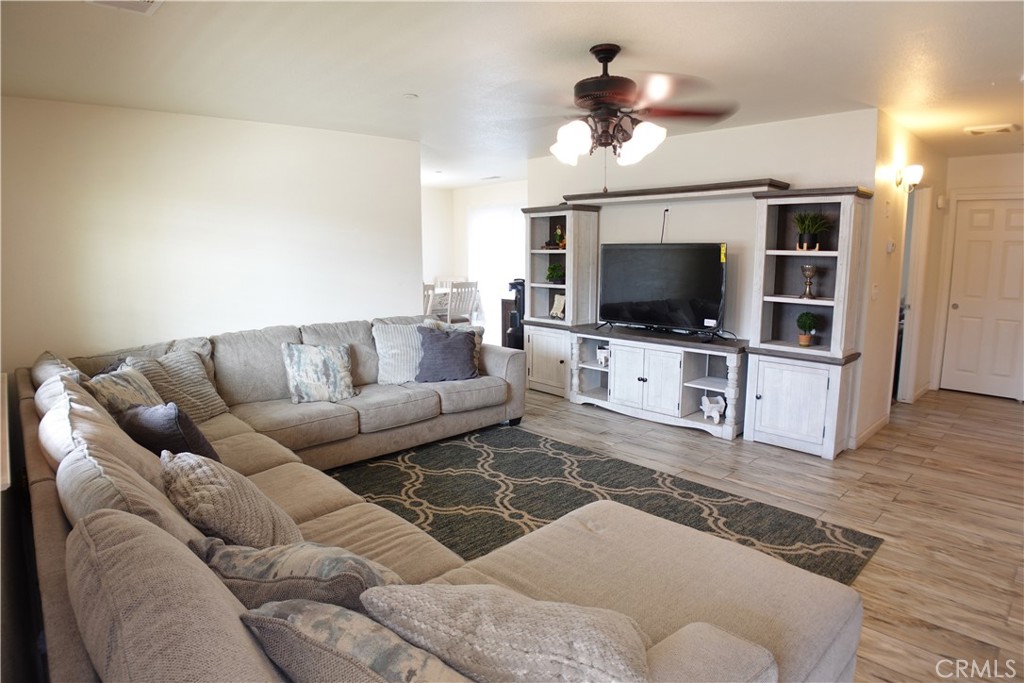 Living room with a beige sectional, patterned rug, and white entertainment center.