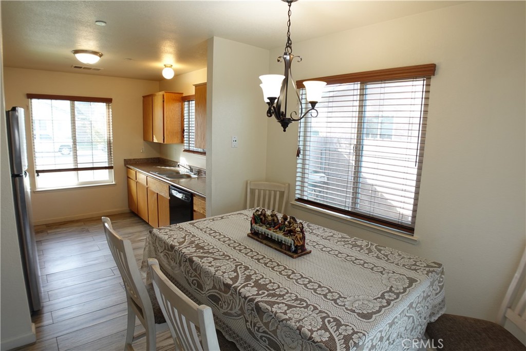 Kitchen and dining area with wood cabinets, stainless steel appliances, and a table beside large windows.