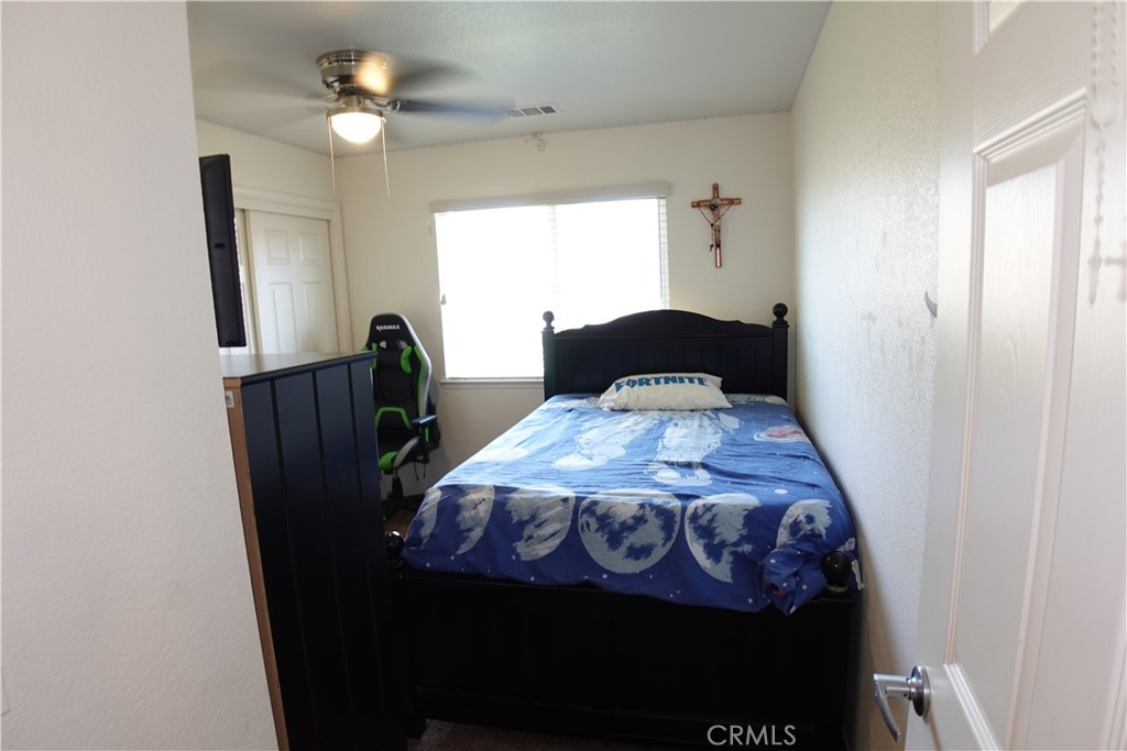 Bedroom with blue moon-patterned bedding, a dark wood bed, and a green-and-black gaming chair.