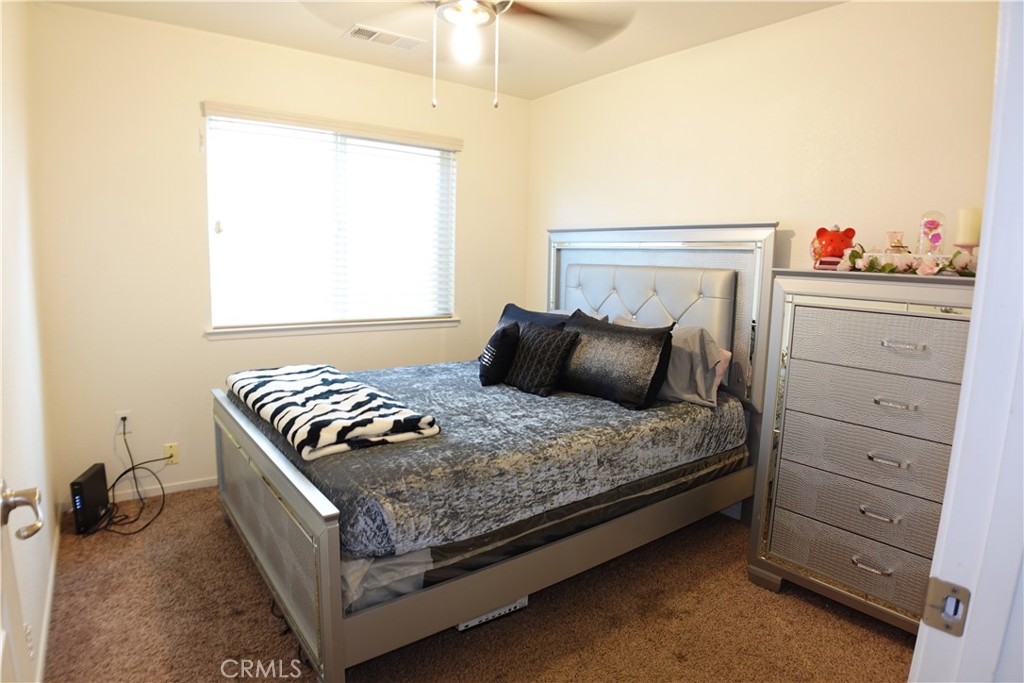 Bedroom with a silver bed and matching dresser beside a window with white blinds.