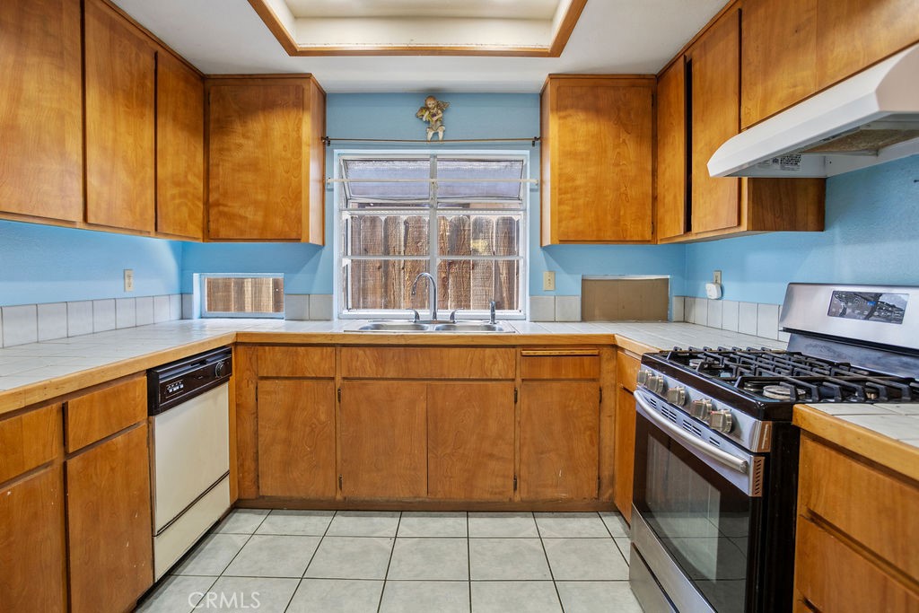 Kitchen with honey-colored wood cabinets, blue walls, and a stainless-steel gas range.