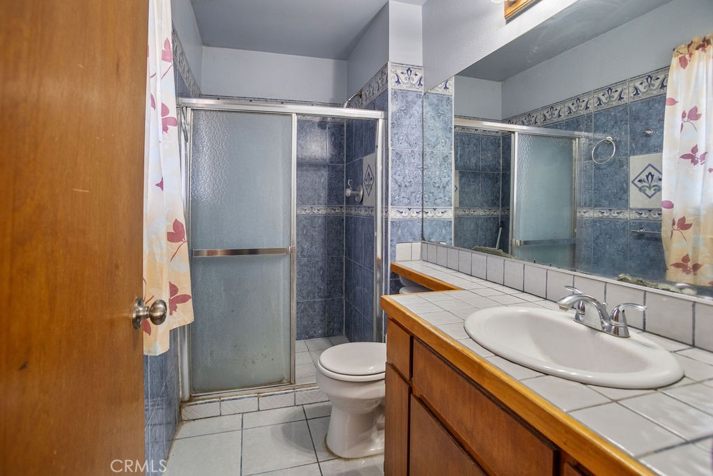 Bathroom with blue patterned tile, a frosted-glass shower, and a long vanity.