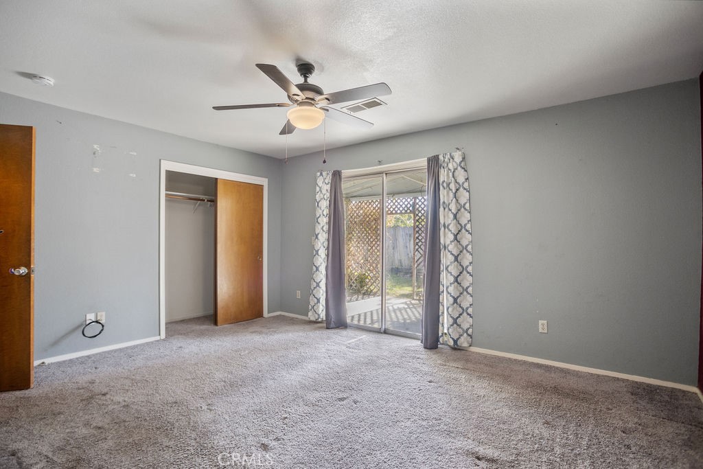 Unfurnished bedroom with a ceiling fan, open closet, and sliding glass doors to a patio.