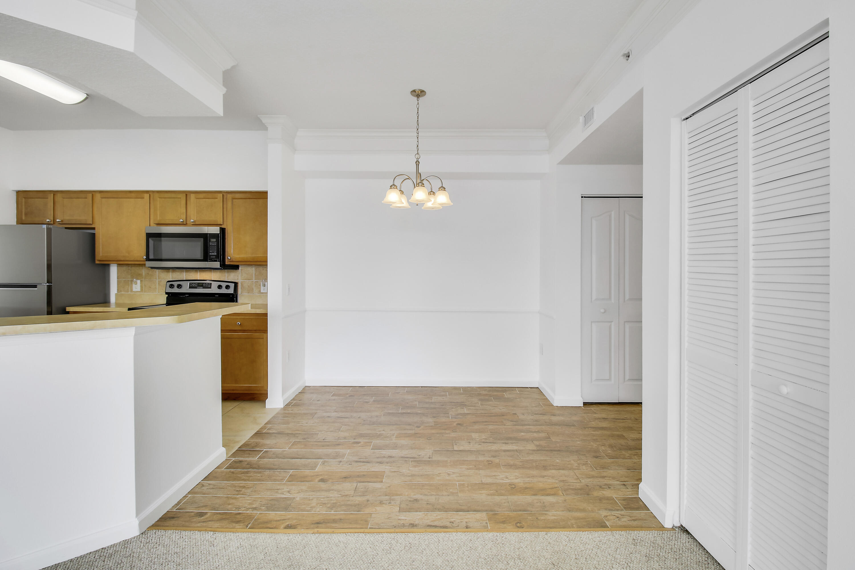Open dining area beside a kitchen with wood cabinets, a breakfast bar, and tan tile flooring.