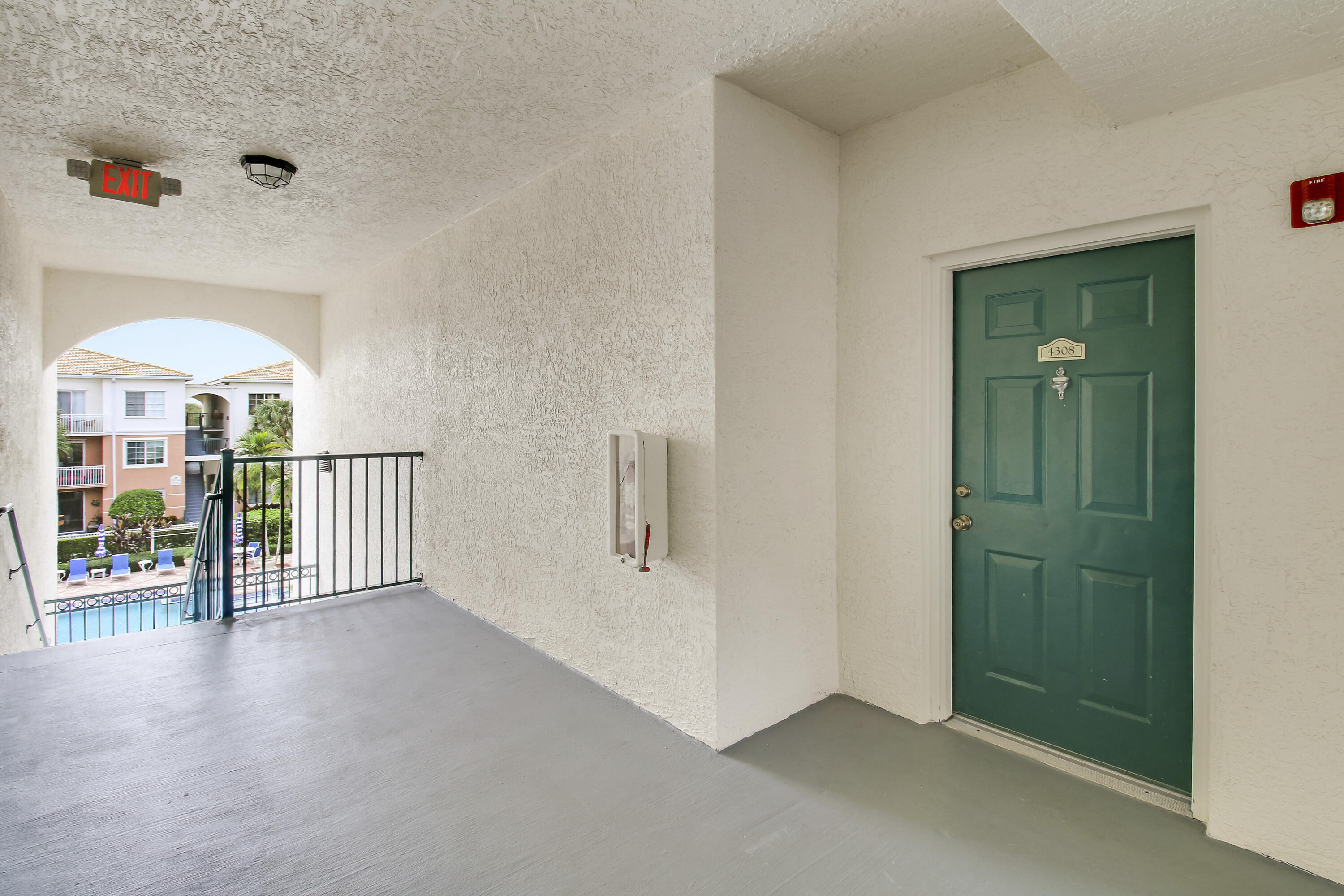Covered condo entry with green door 4308 and an arched view over the courtyard pool.