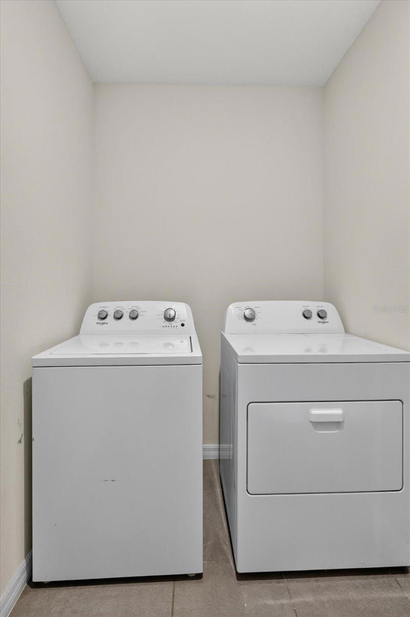 Laundry area with a white top-loading washer and front-loading dryer side by side.