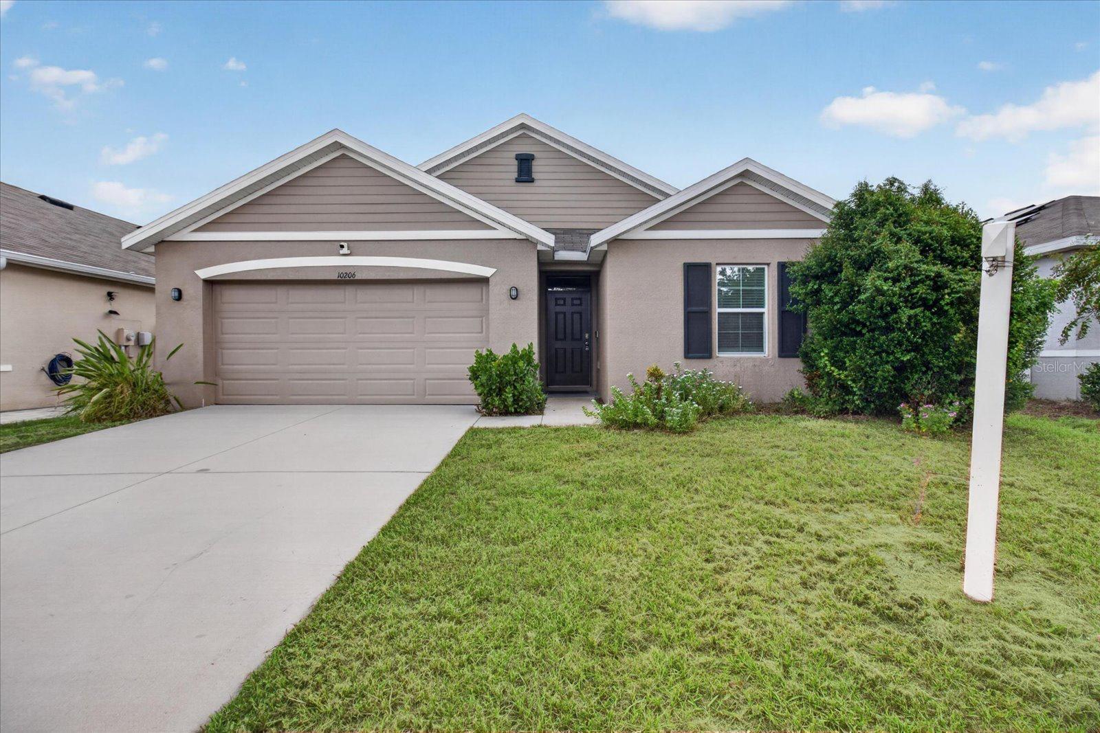 Single-story taupe home with three front gables, a two-car garage, and a broad driveway.