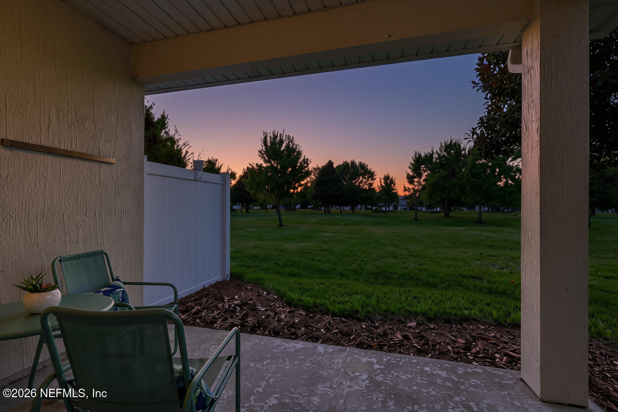 Covered patio with outdoor seating overlooking a tree-lined lawn at dusk.