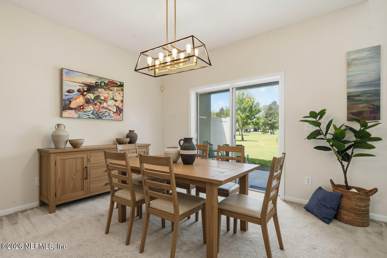 Furnished dining room with a wooden dining set and sliding glass doors overlooking a lawn.
