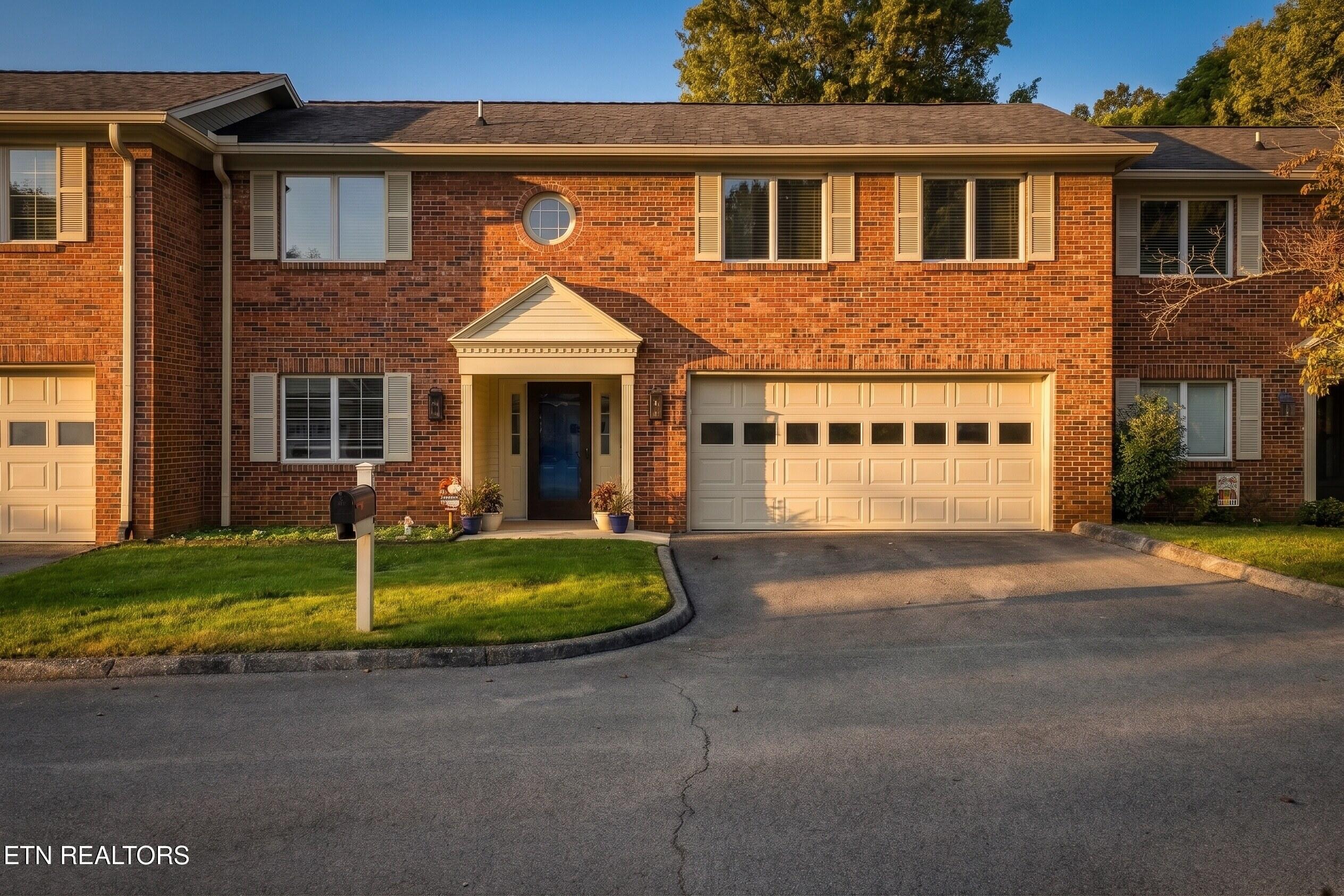 Two-story brick home with a covered entry, circular window, double garage, and front lawn.