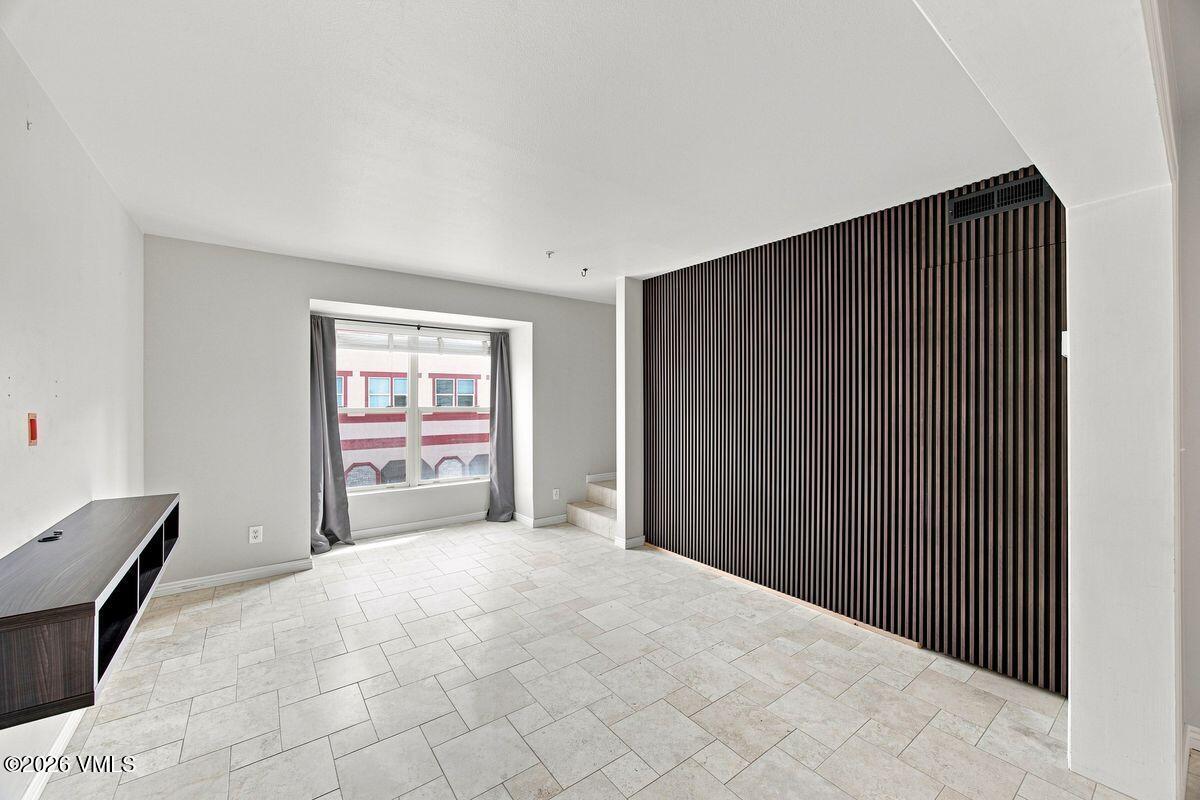 Empty tiled room with a large curtained window and dark vertical-slat feature wall.