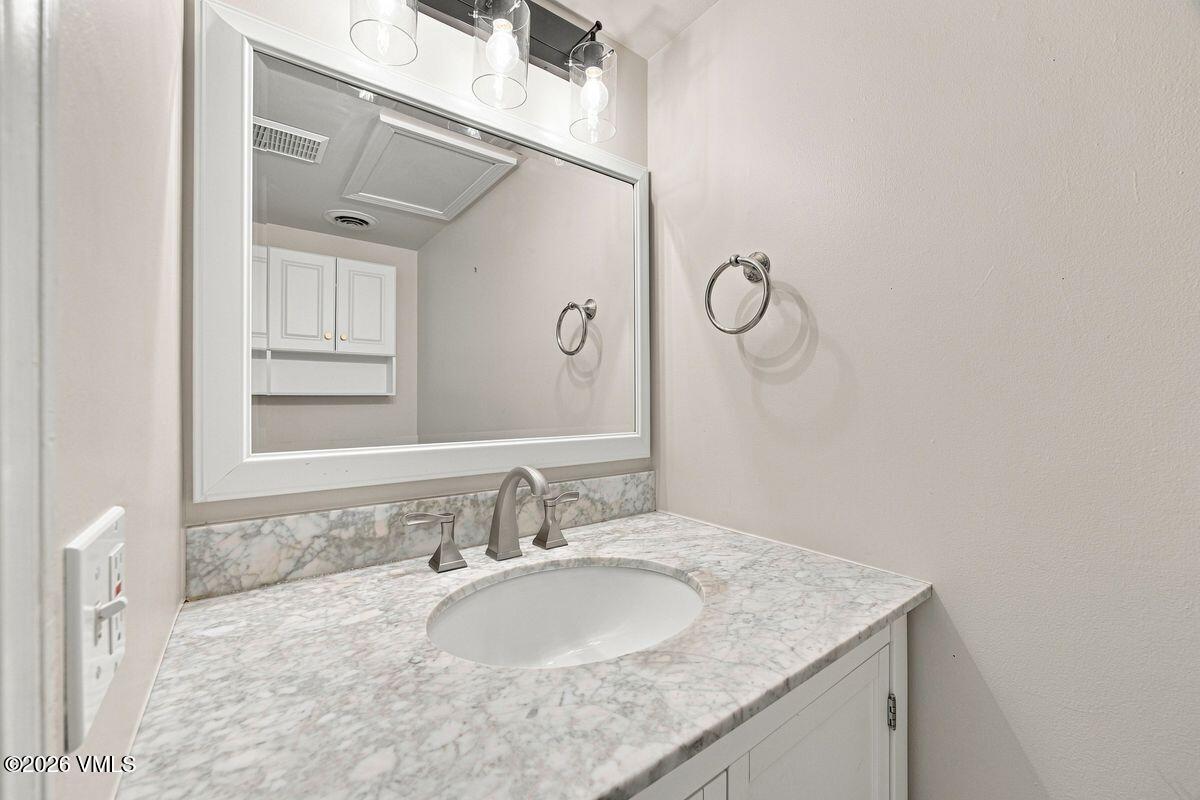 Bathroom vanity with veined marble countertop, oval sink, brushed metal faucet, and large framed mirror.