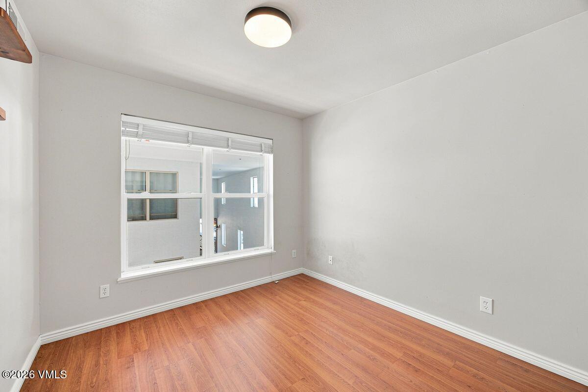 Empty room with wood-look flooring, white walls, and a large multi-pane window.