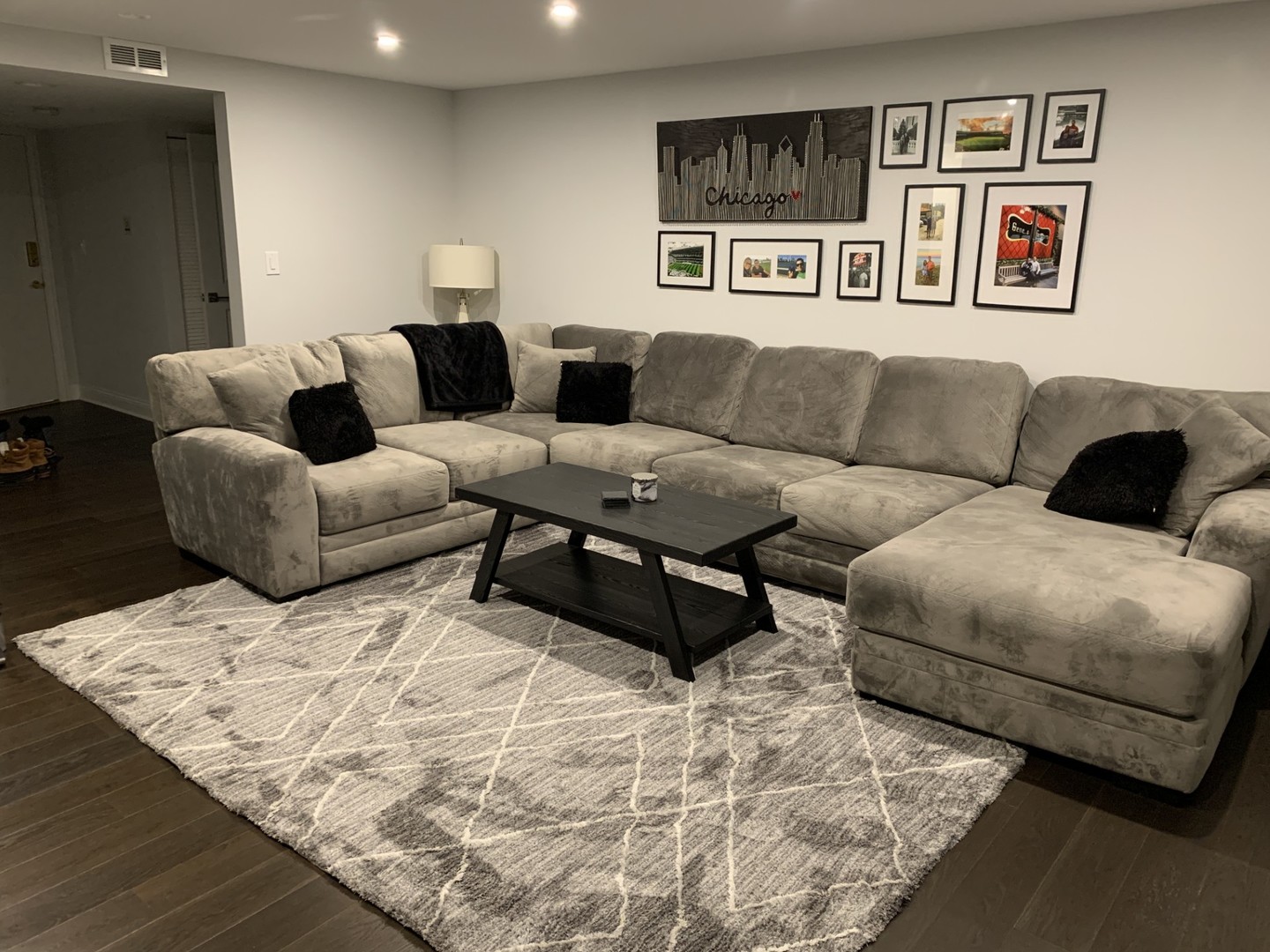 Living room with a gray sectional, black coffee table, patterned rug, and Chicago wall art.