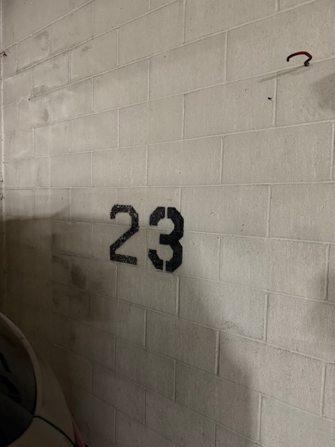 Parking garage space marked 23 on a white cinderblock wall.