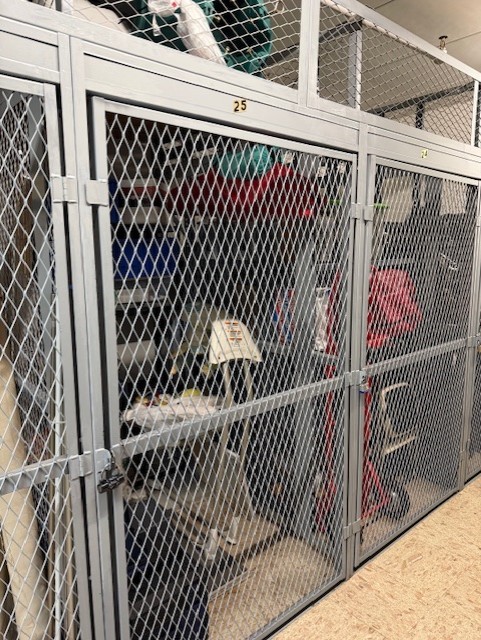 Numbered wire-mesh storage lockers with belongings visible inside.