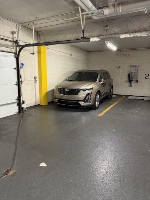 Parking garage with a silver SUV beside a yellow support column and marked parking spaces.