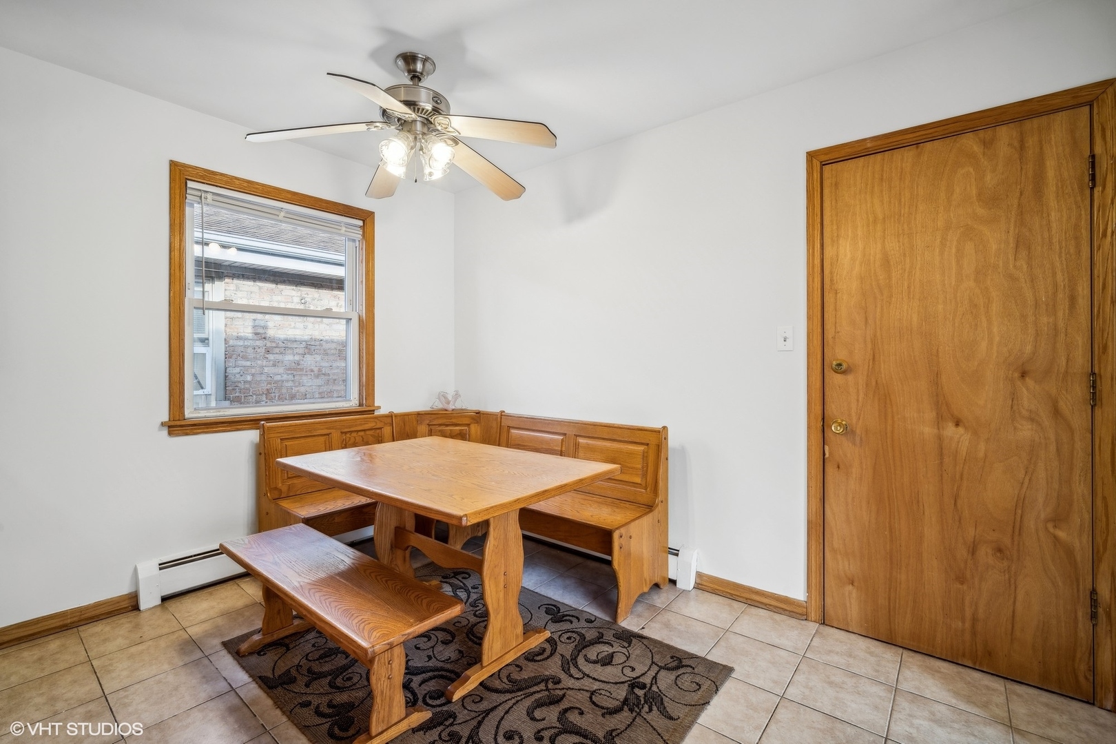 Dining nook with a wooden corner bench and matching table beneath a ceiling fan.