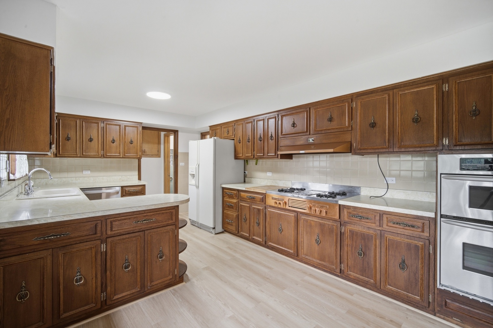 Kitchen with extensive dark wood cabinets, a peninsula, and stainless steel oven.