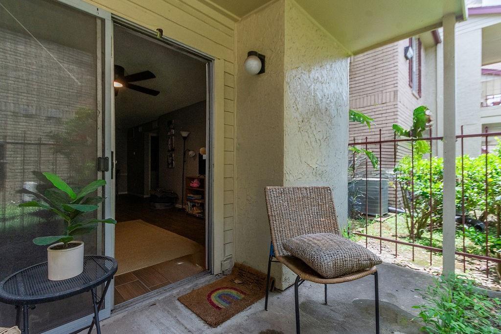 Covered apartment patio with a wicker chair and sliding glass door