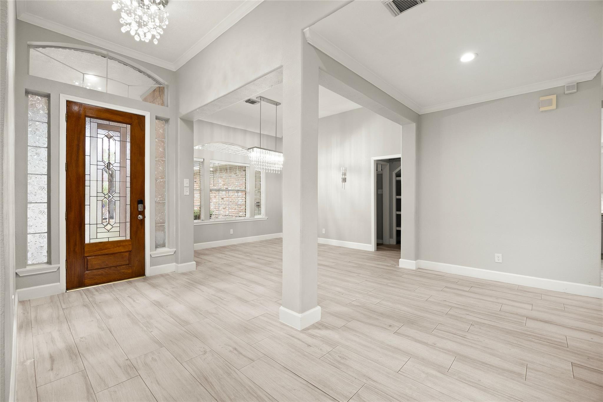 Vacant entry foyer with a decorative wood-and-glass front door and pale tile flooring.