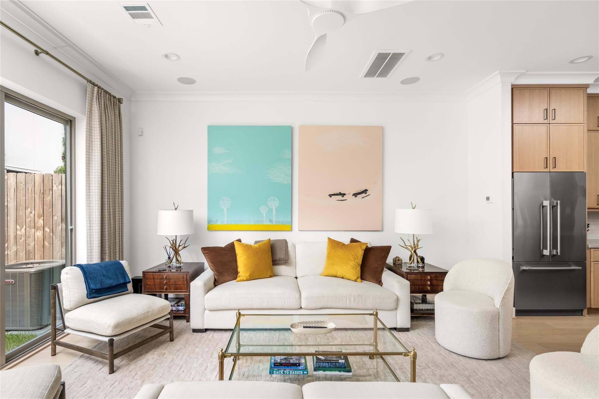 Living room with a white sofa, colorful artwork, glass coffee table, and sliding patio door.