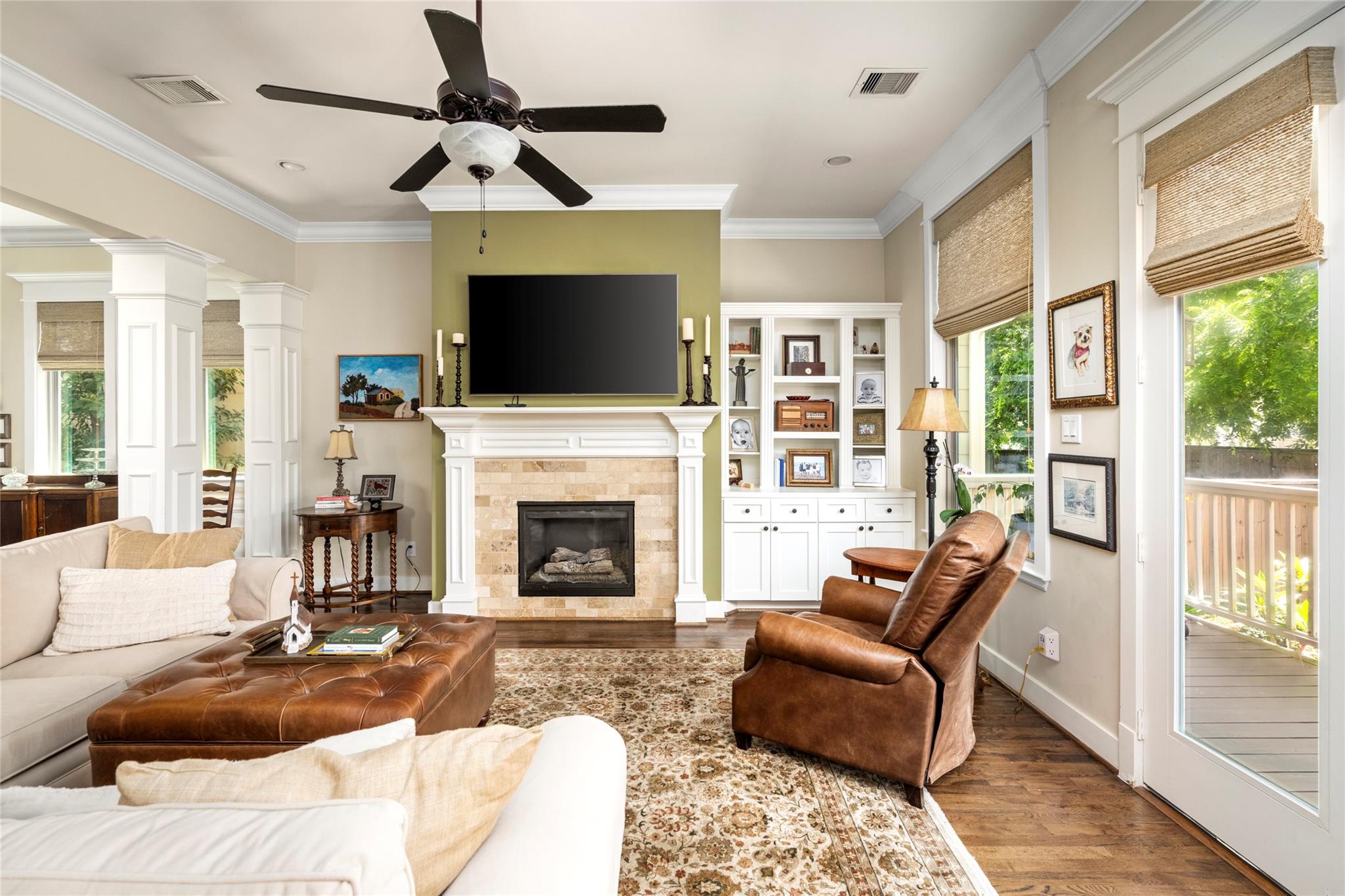 Living room with a white fireplace, built-in shelves, leather seating, and glass doors to a deck.