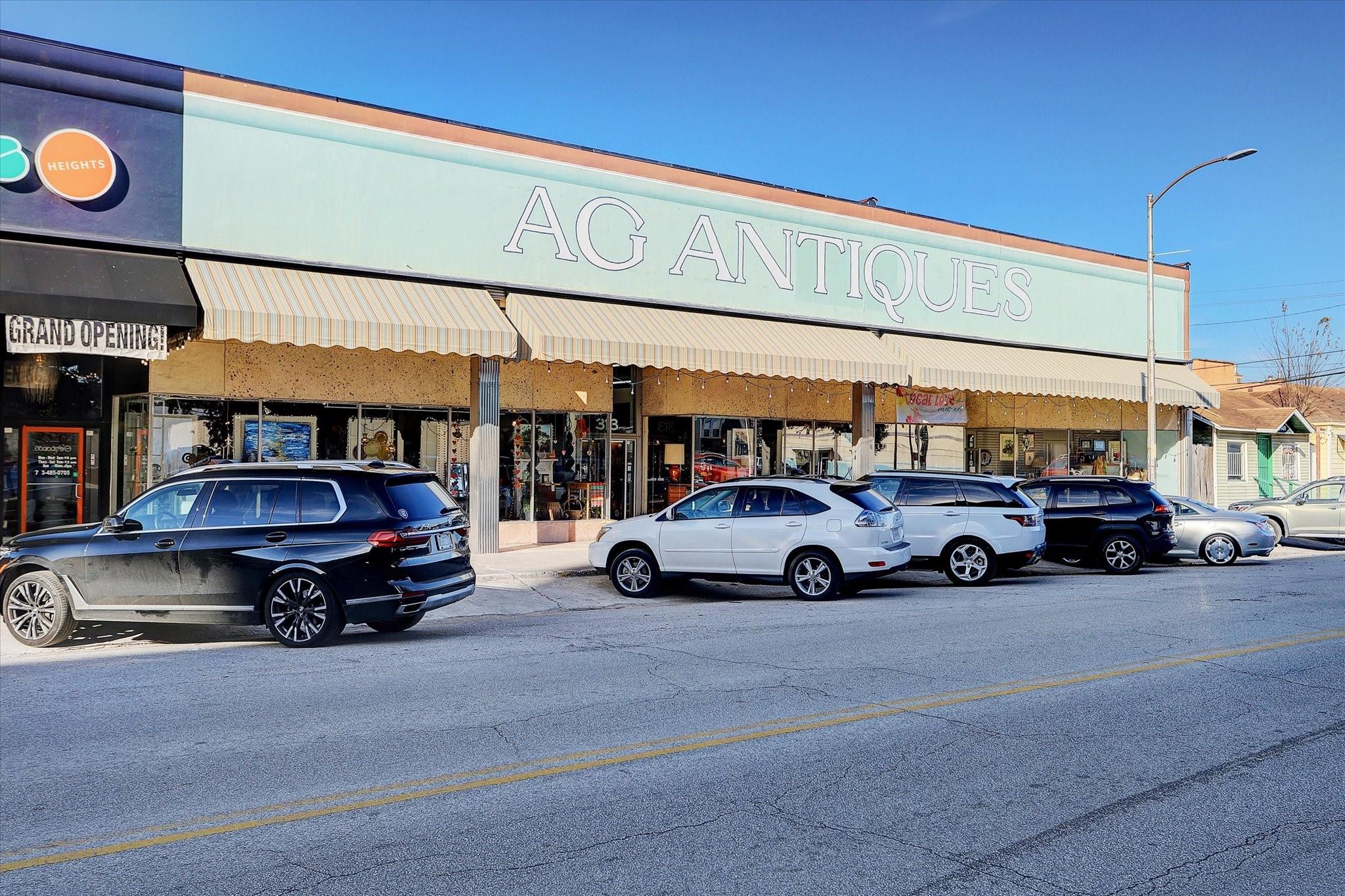 AG Antiques storefront with striped awnings and cars parked along the street.